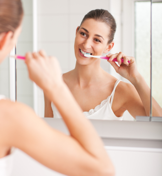 Woman looking into mirror while brushing her teeth