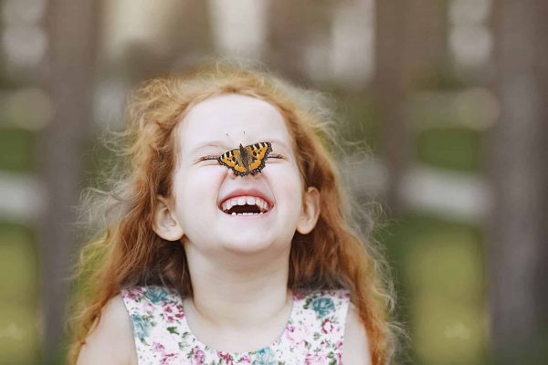 girl with a laughing face butterfly on a nose